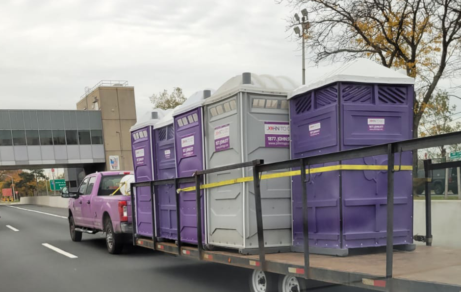 truck on highway transporting porta potty rentals