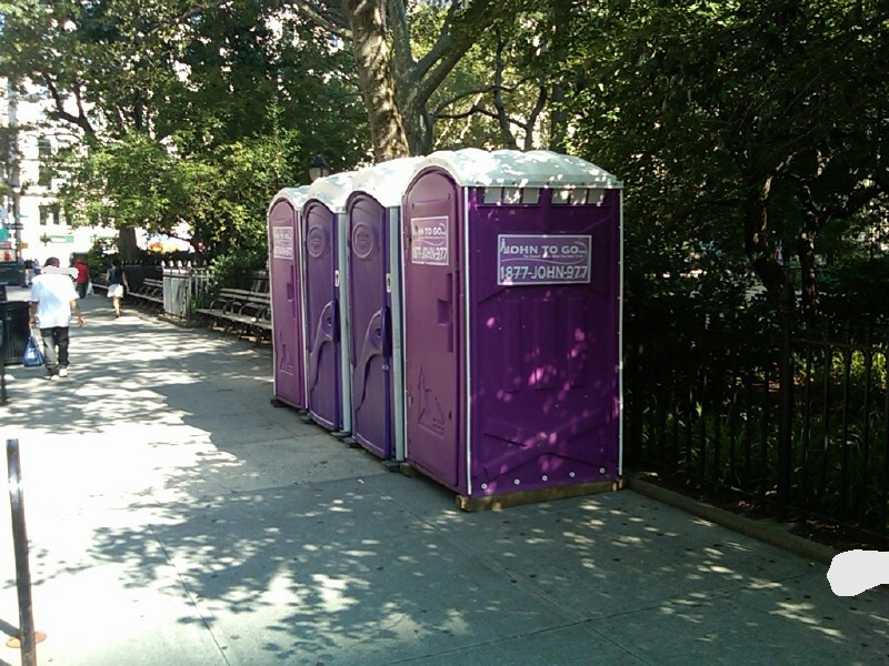 several purple portable toilets for event