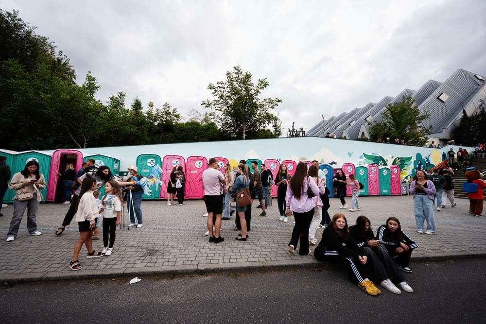 row of colorful porta-poties at an event with a group of people in the foreground